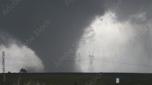 A massive wedge-shaped tornado advances toward the camera over Nebraska farmland