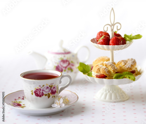 Cream puffs or profiterole filled with whipped cream served with strawberries in plateau on a breakfast table