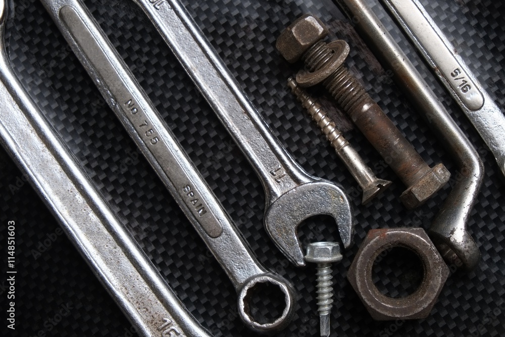 Nut wrenches on a reflective carbon fiber surface with nuts and bolts. Tools and equipment Nut wrenches on a reflective carbon fiber surface with nuts and bolts. Tools and equipment