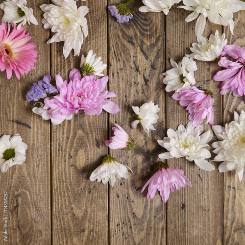 Pink, white and purple flower heads on a wooden background