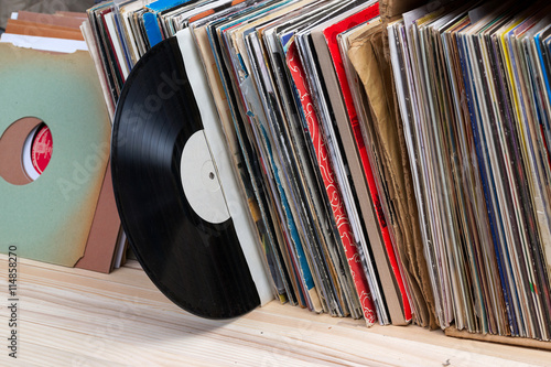 Retro styled image of a collection of old vinyl record lp's with sleeves on a wooden background.  Copy space