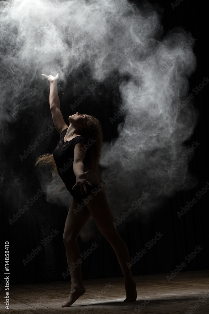 Ballerina dancing with flour on black background