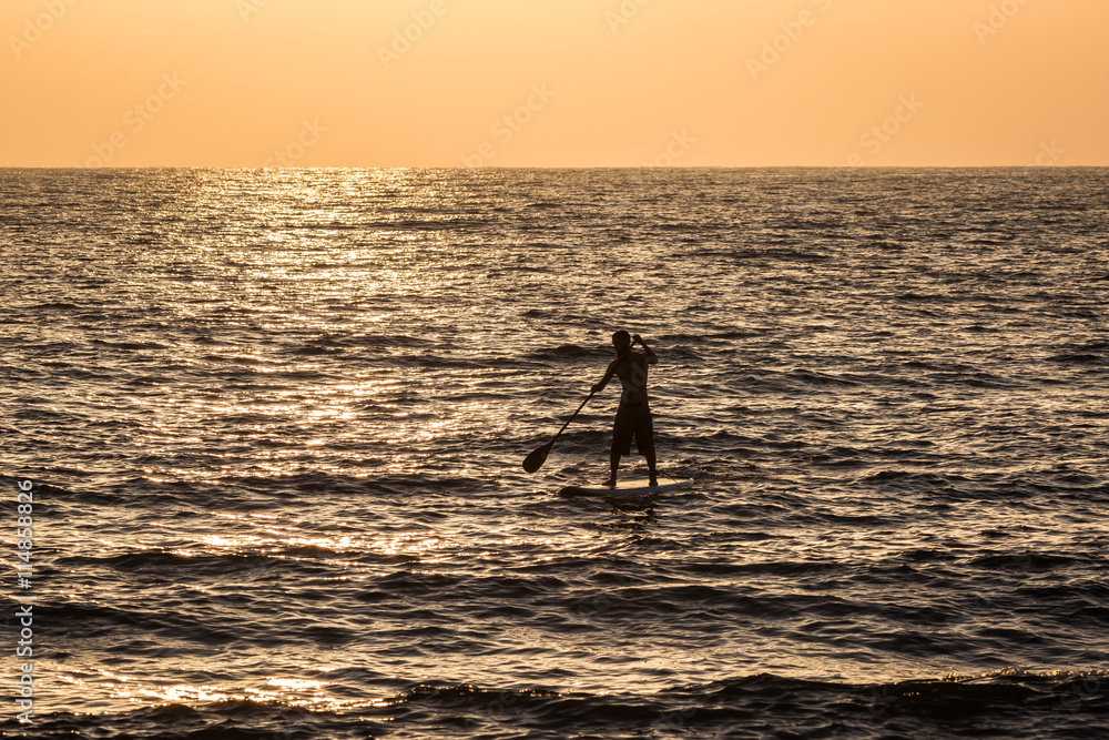 Silhouette of a young man on his sup paddle board during a clear sunset