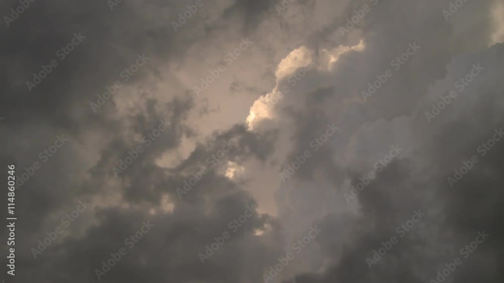 Looking up into a mass of swirling ragged gray clouds in front of billowing sunlit cumulus Looking up into a mass of swirling ragged gray clouds in front of billowing sunlit cumulus