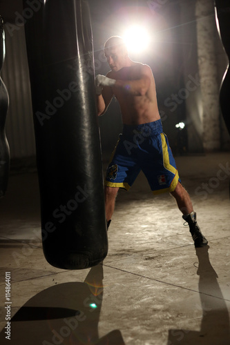 African American male boxer hitting punch bag in the gym