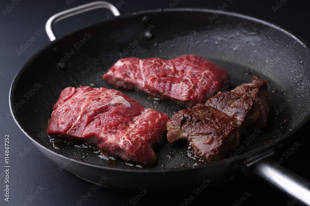 Fresh tenderloin steaks in frying pan. Bkack backfround Fresh tenderloin steaks in frying pan. Bkack backfround