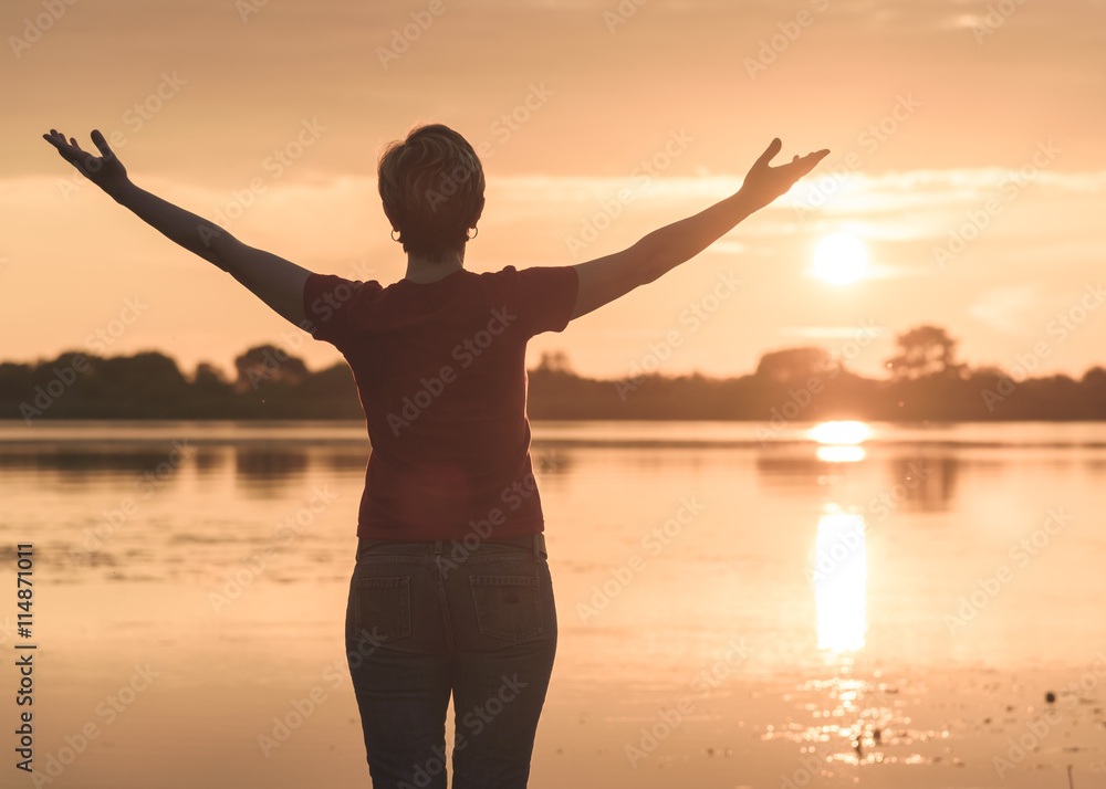 Fototapeta premium young slim woman meditating onbanks of the lake at sunset