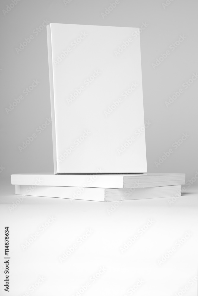 Real paperback white book over a stack of books on a gray background Real paperback white book over a stack of books on a gray background