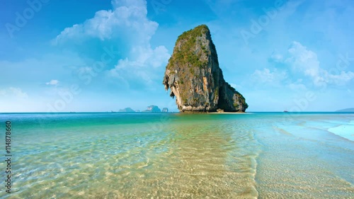 Video 2160p - Enormous limestone formation, jutting skyward against a bold, blue horizon, from the warm shallows of a tropical sea.