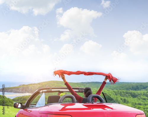 Girl in a red convertible car on background seascape.
