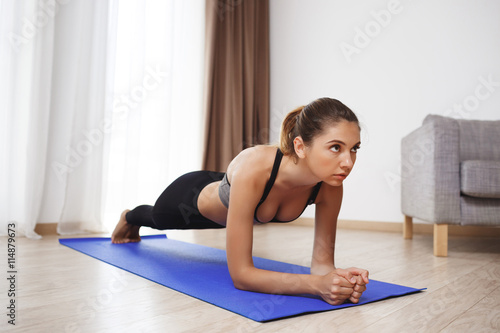 Beautiful fitness girl making plank exercises on floor 