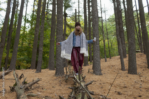 Young woman walking on tree trunk in forest