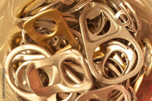 Background of many ring pull can opener, silver and gold.
