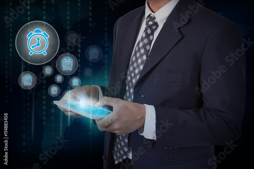 Wallpaper Mural Businessman hand touch alarm clock icons on a tablet. Torontodigital.ca