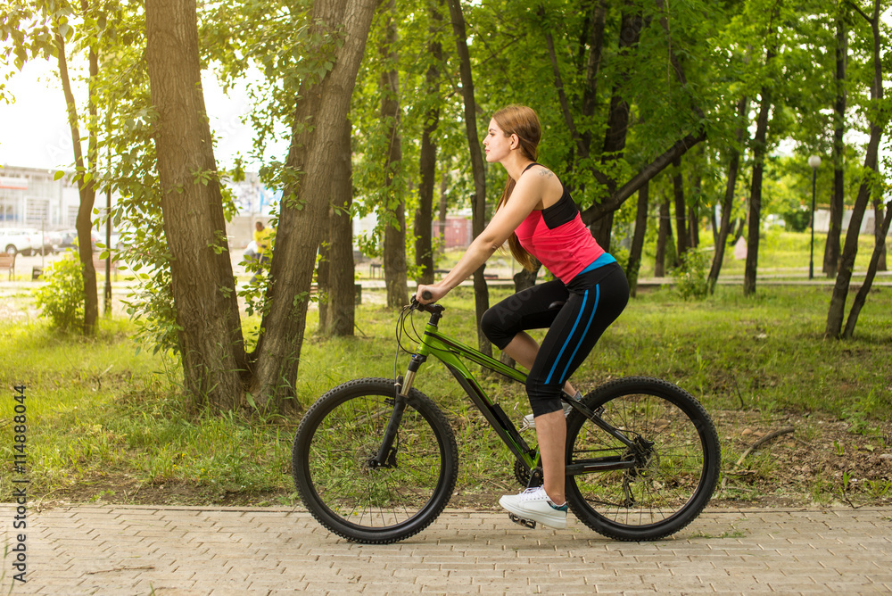 Happy girl cyclist riding on a mountain bike outside