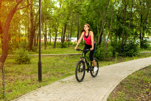 Happy girl cyclist riding on a mountain bike outside © Artem