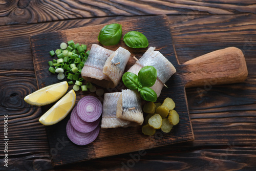 Top view of a rustic wooden serving board with herring rolls