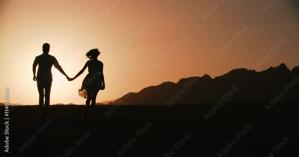 couple silhouette running forward holding hands with the sunset Golden hour, the sun a warm color, slow motion couple silhouette running forward holding hands with the sunset Golden hour, the sun a warm color, slow motion