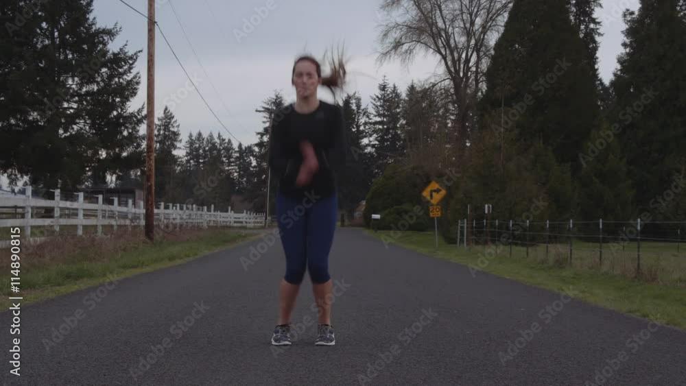 Attractive Young Adult Female stretch-jumping Before Run on Country Road Attractive Young Adult Female stretch-jumping Before Run on Country Road