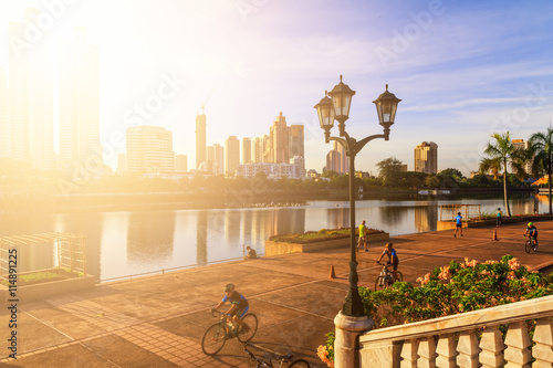 Morning in the park ,young boy and girl bike ride and jogging.
 Park and River in the downtown area. photo