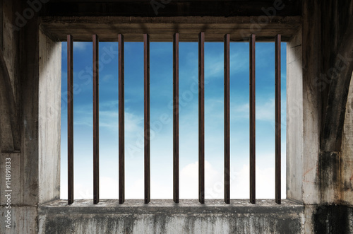 Old window frame with iron bar in jail  and blue sky