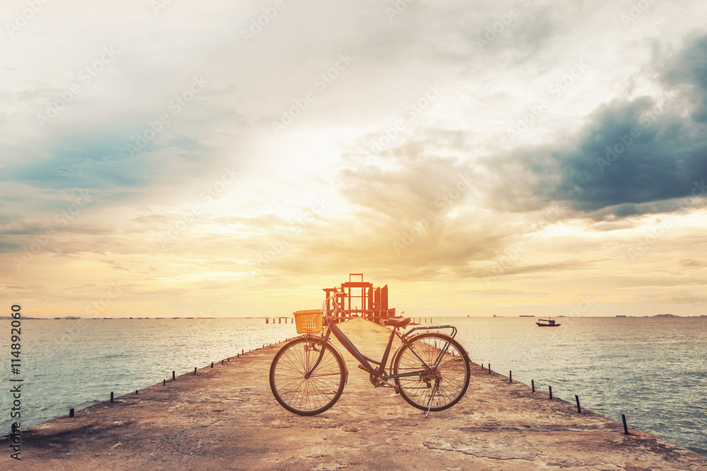 Fototapeta premium Vintage bicycle on concrete pier in sunset, vintage tone, soft focus