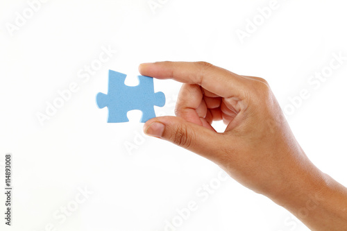 Hand holding jigsaw piece against white background