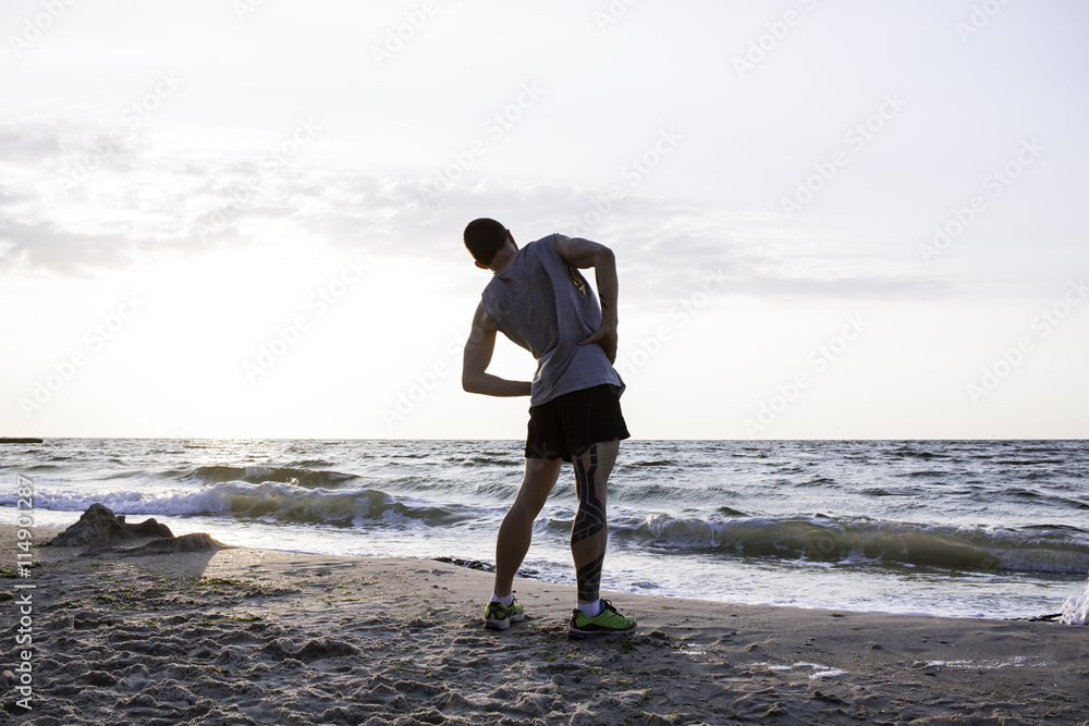 sporty tattooed man  doing exercises on beach