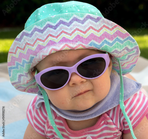 Baby mit Sonnenhut und Sonnenbrille im Garten photo