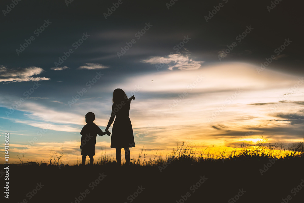 Silhouette of Mother encouraged her son outdoors at sunset, silh Silhouette of Mother encouraged her son outdoors at sunset, silh
