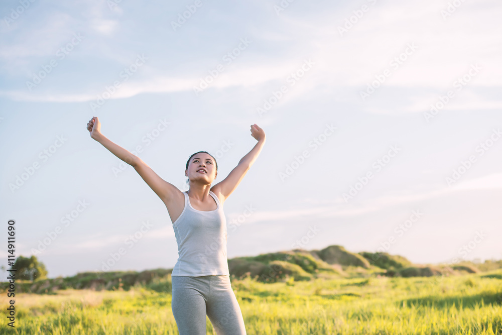 Happy beautiful woman with stretched arms in meadows with fresh