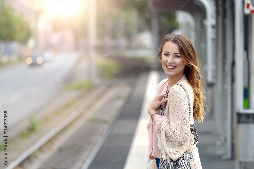 Fototapeta premium Attraktive Frau wartet an einer Haltestelle