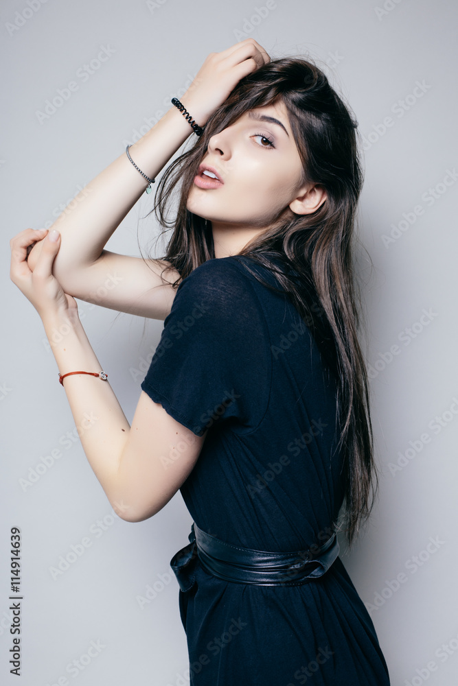 Young brunette lady in black dress posing on grey background Young brunette lady in black dress posing on grey background