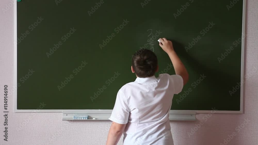 Teen student solves an example on the blackboard Teen student solves an example on the blackboard