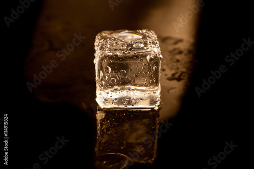 ice cube on the black background reflection with golden light, P © peterkai