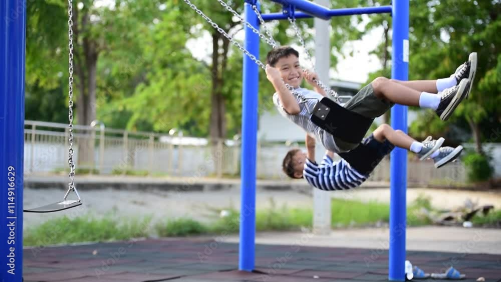 Two young asian boy play a iron chain swinging at the playground under the sunlight in summer. Two young asian boy play a iron chain swinging at the playground under the sunlight in summer.