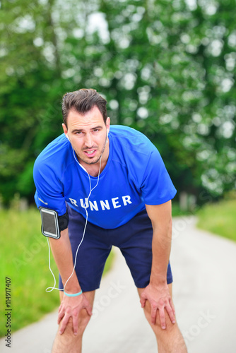 Portrait Of Male Jogger Standing In Field While Listening Music