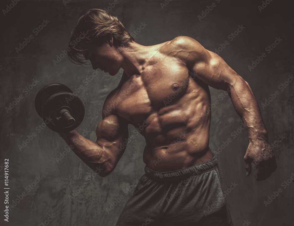 Portrait of sporty shirtless male with dumbbell.