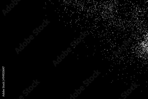 Abstract grainy texture isolated on black background. Silhouette of food flakes such as salt or almond or wheat flour spread on the flat surface or table. Top view. Dust, sand blow or bread crumbs.