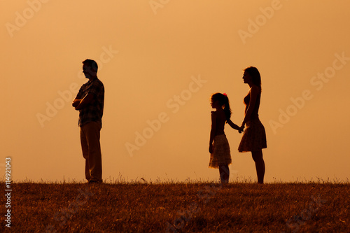 Silhouette of a angry husband  turning back while his wife and daughter are looking at him.