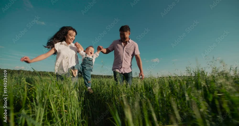 happy Asian family with small child 1 year running on the green field, slow motion happy Asian family with small child 1 year running on the green field, slow motion