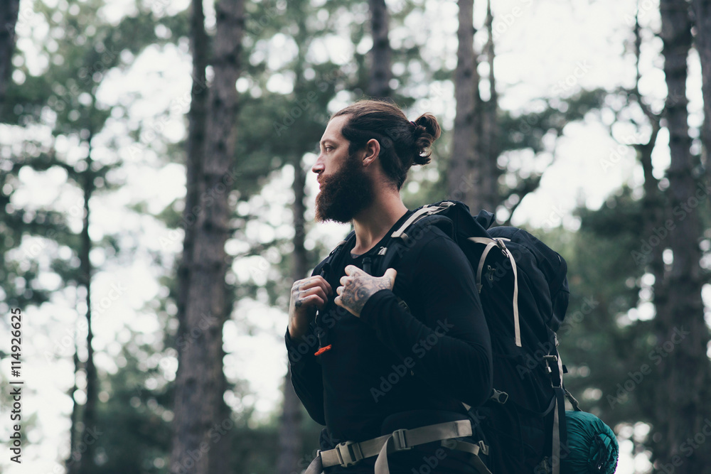 Obraz premium Bearded man with backpack trekking in forest