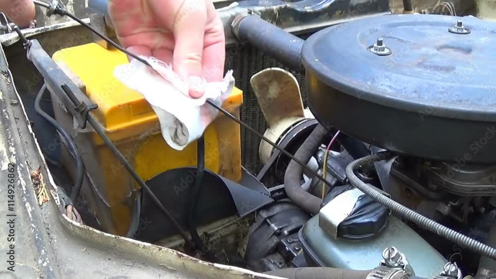 Pulls out the oil dipstick in her car engine to check the lubricant ...