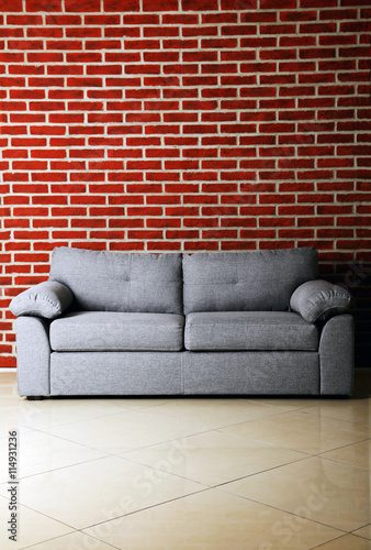 Grey sofa on a red brick wall background