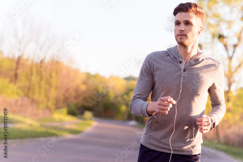 Fototapeta Naklejka Na Ścianę i Meble -  Cheerful young jogger running in park