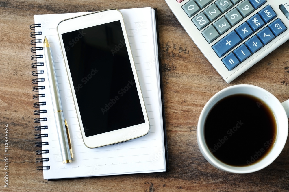 Business finance concept, smart phone, pen, notepad, coffee and calculator on a wooden table. Business finance concept, smart phone, pen, notepad, coffee and calculator on a wooden table.
