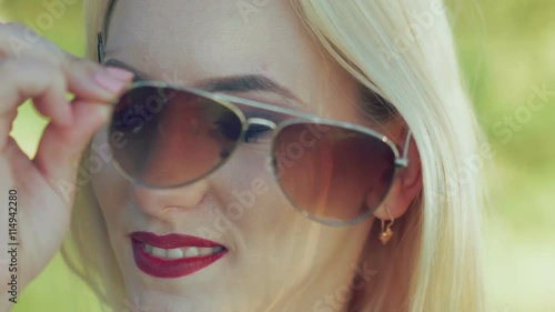 Sexy blonde with claret lips gets off sunglasses. Slowly photo