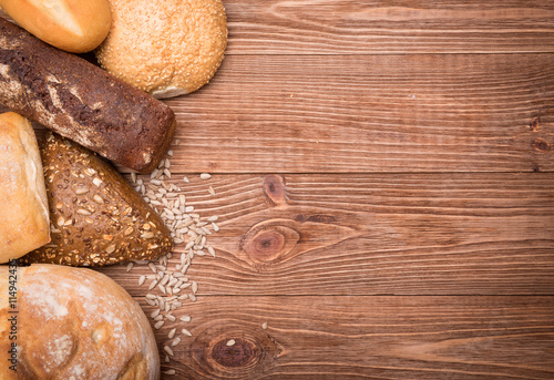 Assortment of baked bread on wooden table background.