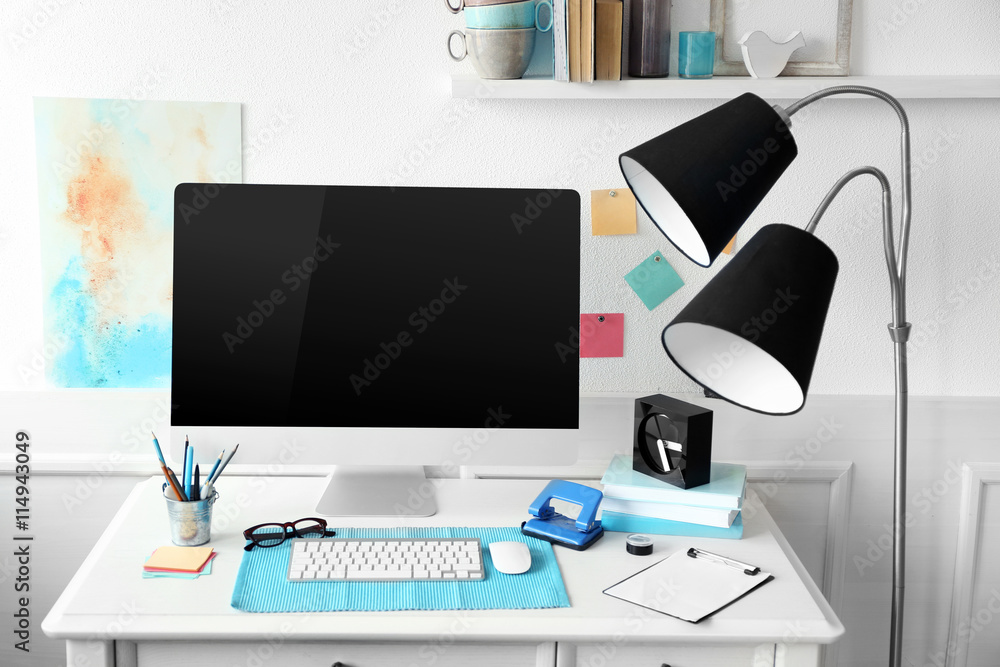 Modern wide screen monitor with lamp on white table in room interior Modern wide screen monitor with lamp on white table in room interior