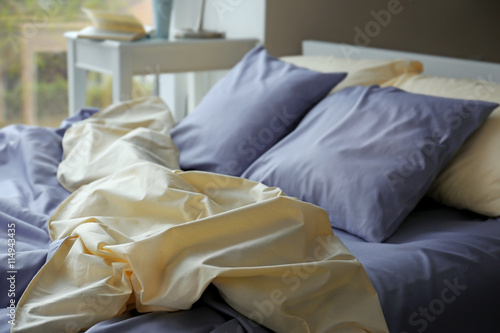 Unmade bed with crumpled blue bed linens
